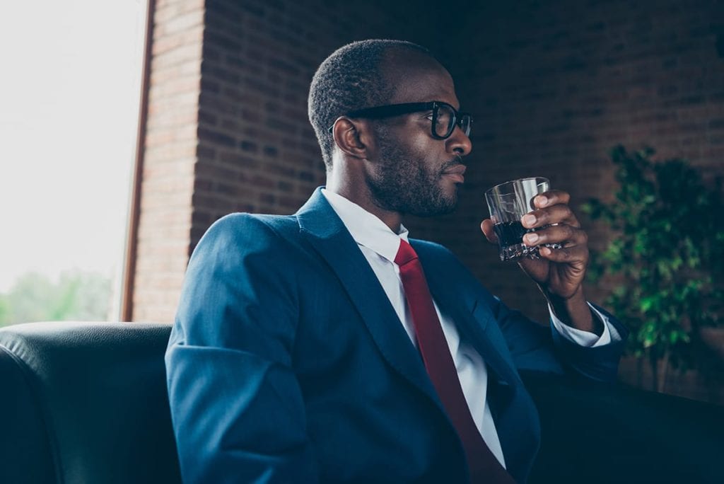 A man takes a drink and wonders how to recognize a functioning alcoholic at work
