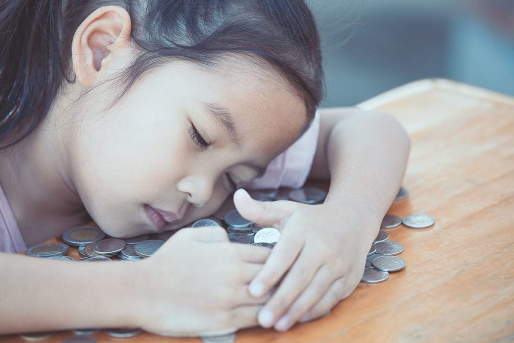 a little girl show early signs of hoarding in children, as she falls asleep on top of her coins