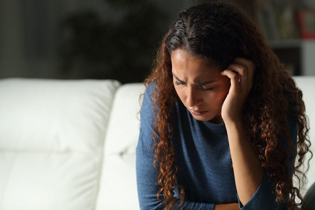 a woman hangs her head and wonders how to help a loved one suffering from post acute withdrawal