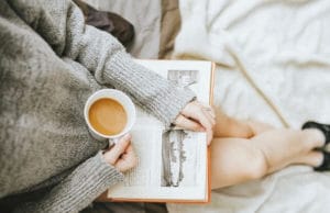woman sits with crossed legs drinking coffee and reading a book about inpatient depression treatment centers
