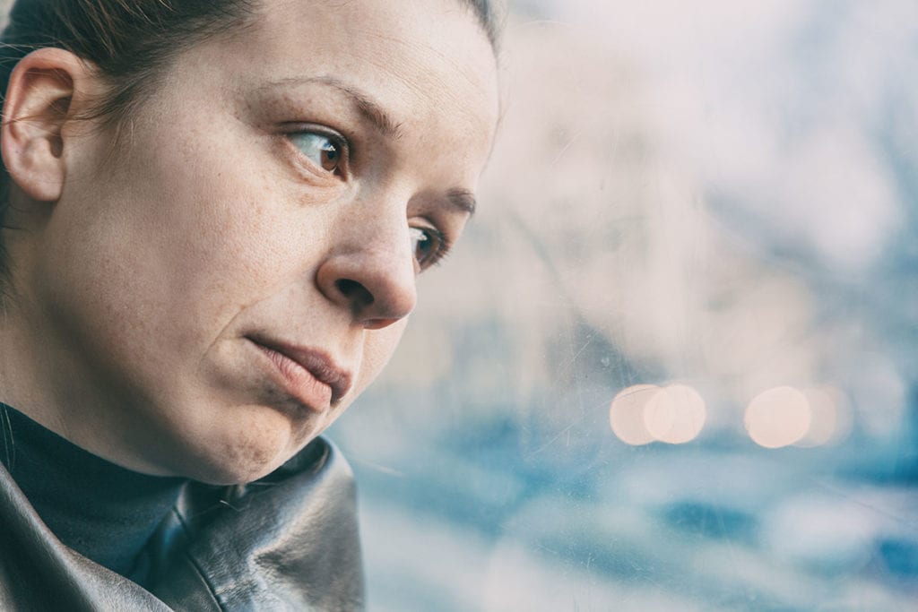 woman leans head on window while wondering is addiction a disease
